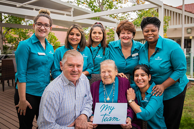 baptistcare aged care workers and chaplain with a nursing home resident with a myteam sign
