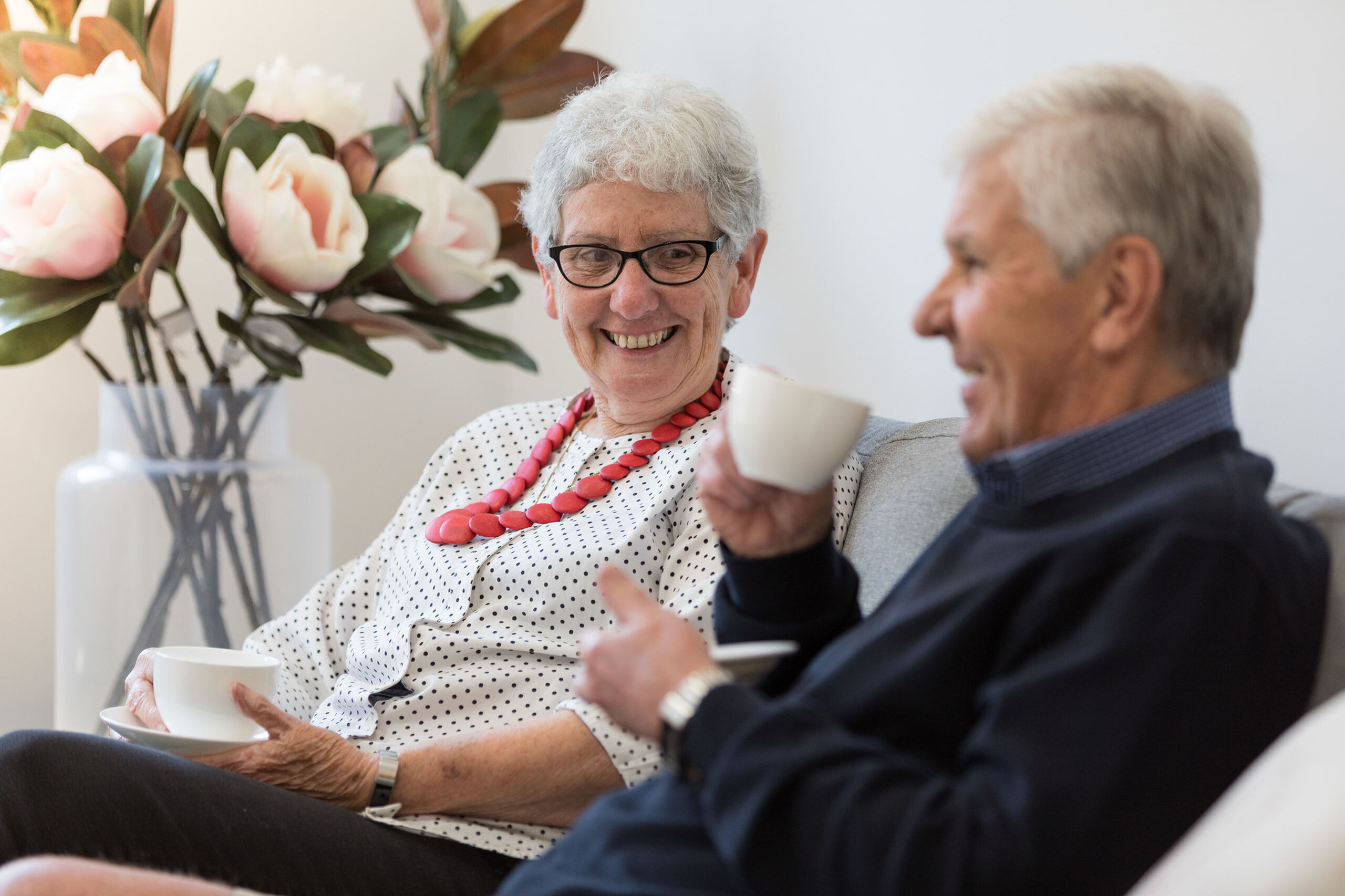 independent over 55s couple enjoying tea in the modern living room of their baptistcare retirement village apartment