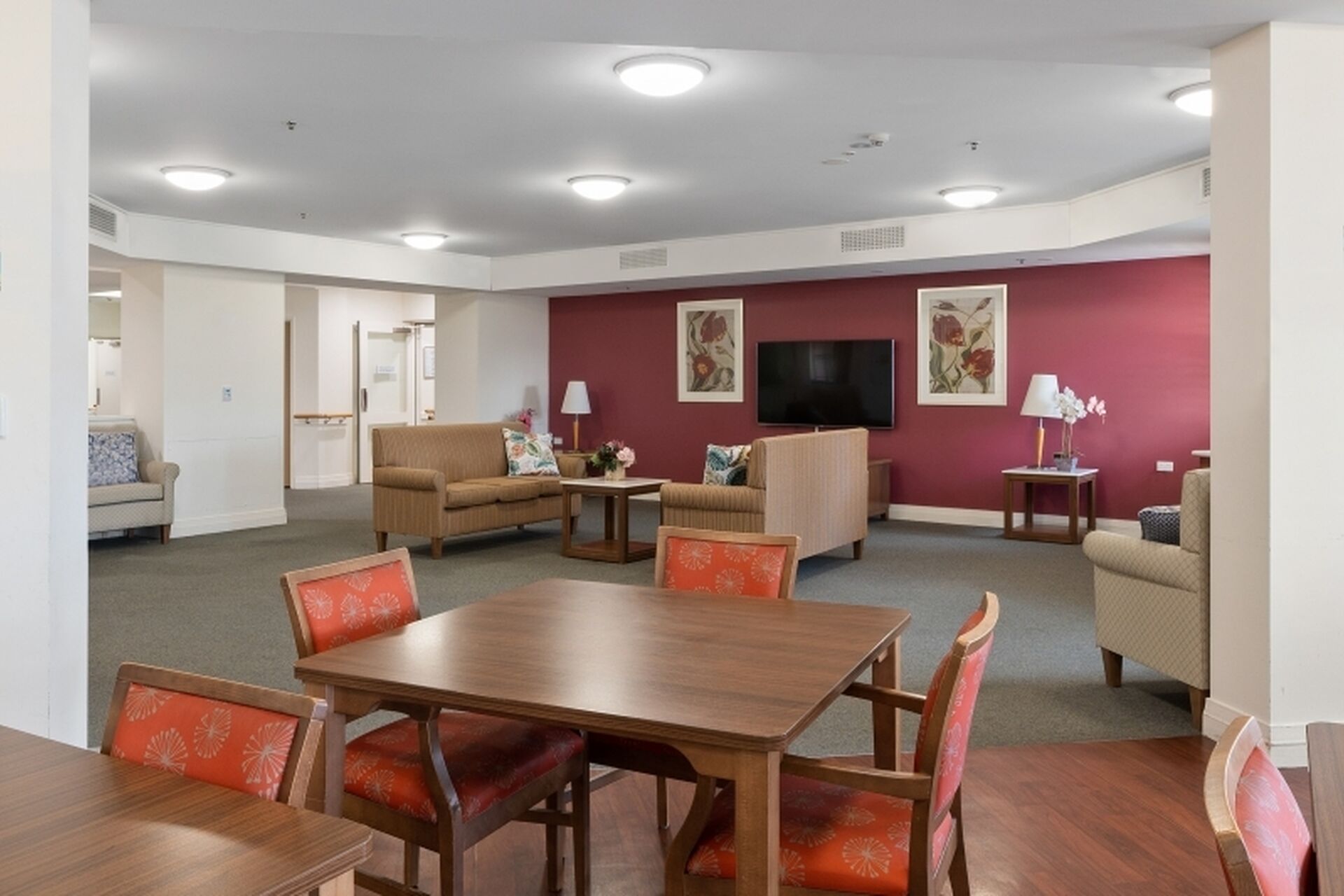 large communal lounge room with aged care residents socialising and watching television at baptistcare warena centre in bangor sutherland shire nsw