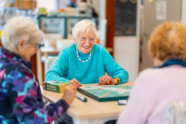 three over55s independent living ladies enjoying tea in the community centre of the retirement village for downsizing