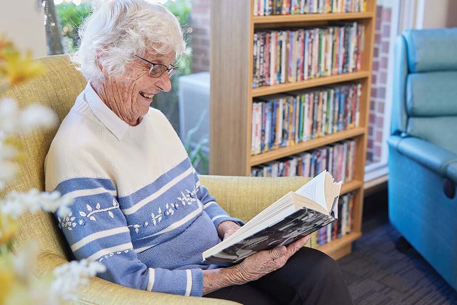 aged care resident enjoying reading a book in the library at baptistcare bethshan gardens centre aged care home in wyee nsw lake macquarie
