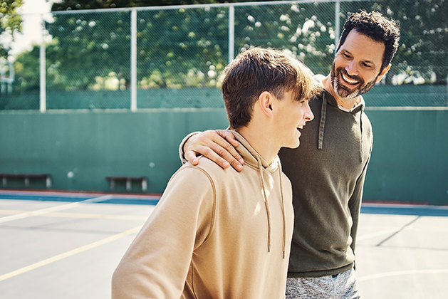 Man with arm around teenage boy who is holding a basketball