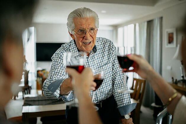 Senior man raising wine glass with friends