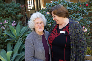 senior aged care resident smiling with a baptistcare aged care chaplain outside of the nursing home