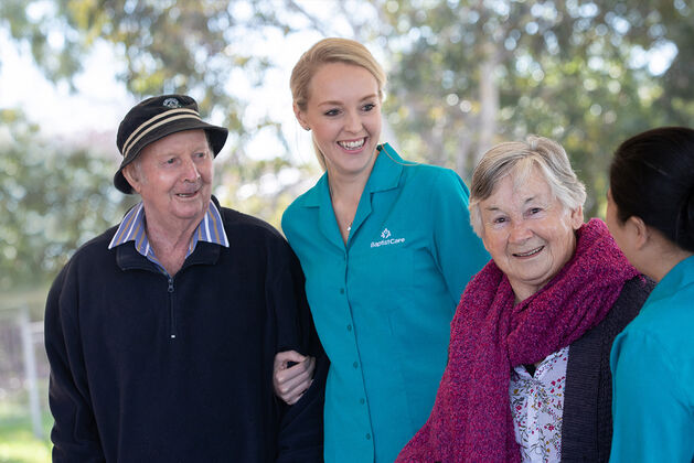 two baptistcare residential aged care residents enjoying a walk through the gardens with baptistcare aged care workers