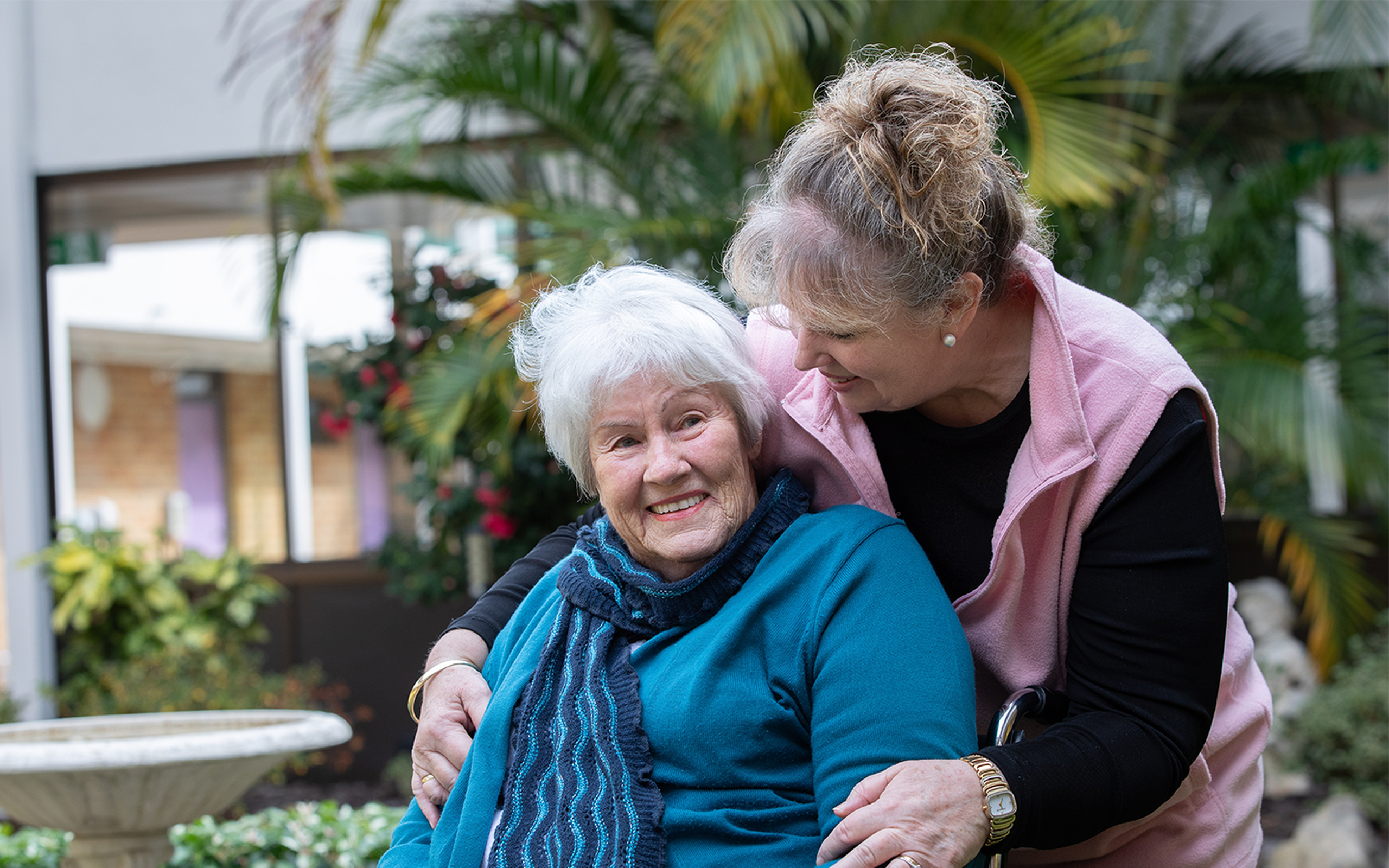 smiling resident of aged care home being embraced outside of the nursing home