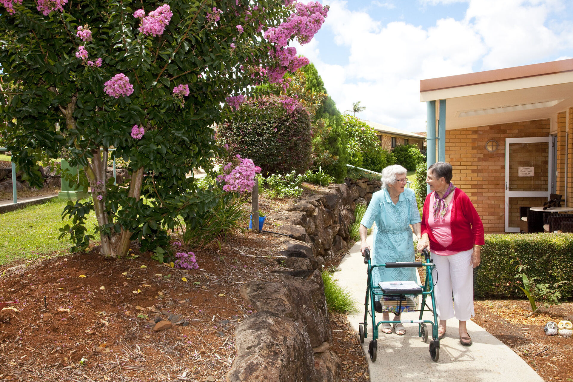 two aged care residents walking through the gardens at baptistcare maranoa centre aged care home in alstonville nsw far north coast