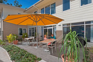 modern two story aged care home with outdoor sitting area covered by a large umbrella overlooking beautiful gardens at baptistcare orana centre aged care home in point clare nsw aged care near gosford central coast