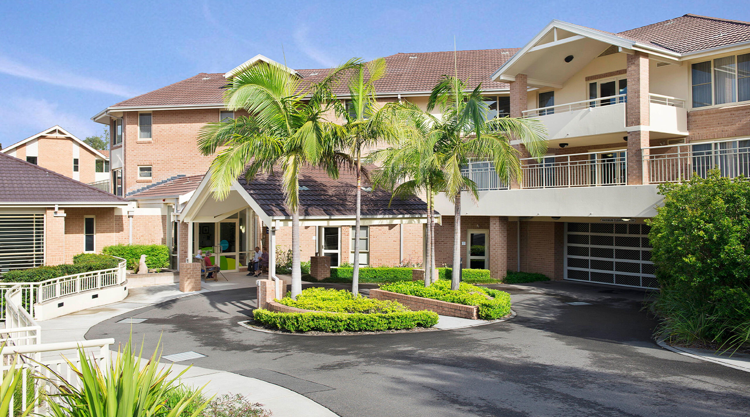 modern aged care home with long driveway and footpath lined with beautiful gardens and large trees at baptistcare warena centre in bangor aged care in sutherland shire nsw