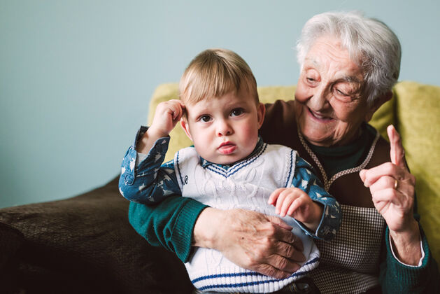 elderly aged care home resident enjoying time with her grandson in her nursing home room
