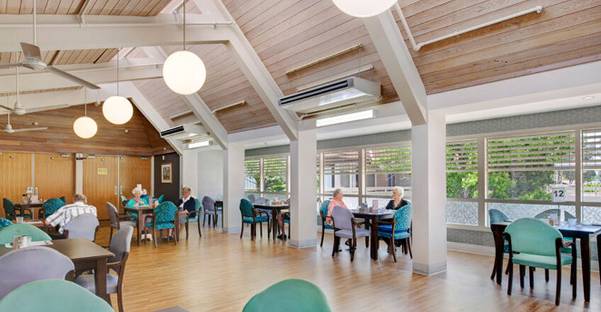 large sitting area with tables and chairs for nursing home residents at baptistcare aminya centre residential aged care home