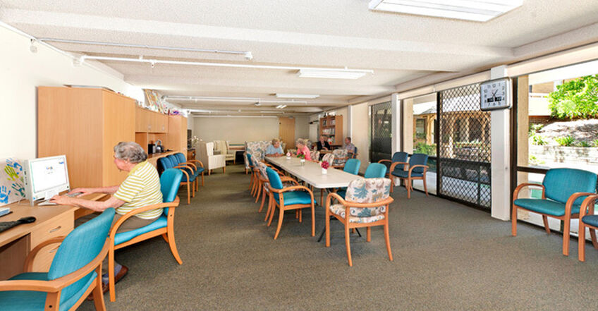 large sitting area with tables and chairs for games and computer use for nursing home residents at baptistcare aminya centre residential aged care home