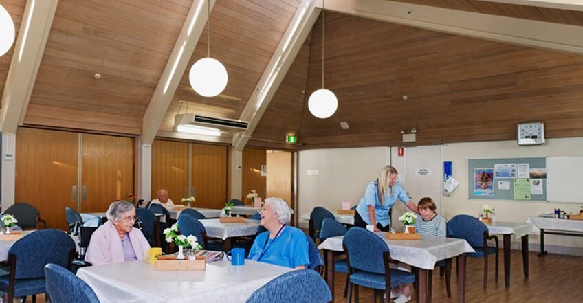 large communal space with tables and chairs for elderly aged care residents to socialise in baptistcare aminya centre residential aged care home