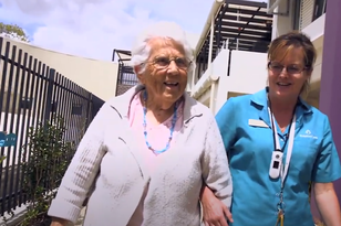 elderly dementia aged care home resident enjoying a walk outside in the sun with baptistcare care service employee at baptistcare carey gardens nursing home