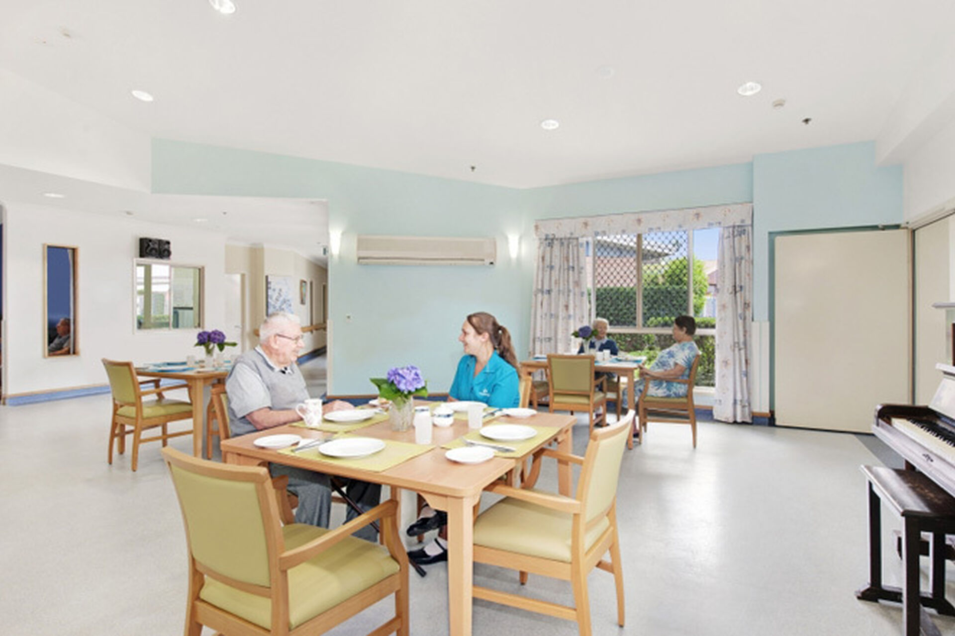 an aged care resident and baptistcare aged care worker sitting in the spacious dining room and sitting room at baptistcare maranoa centre aged care home in alstonville nsw far north coast