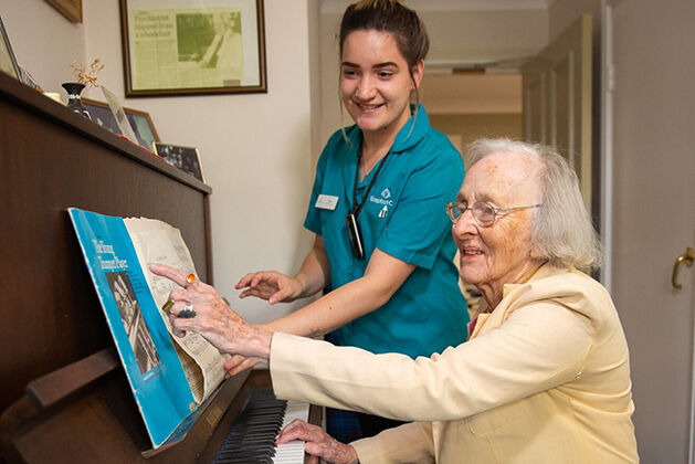 dementia care aged care home resident enjoying music with aged care worker in nursing home