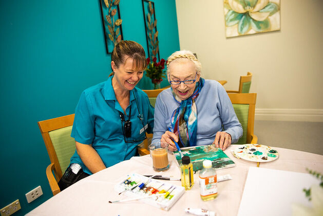 elderly aged care resident enjoying art and craft with baptistcare aged care worker in nursing home