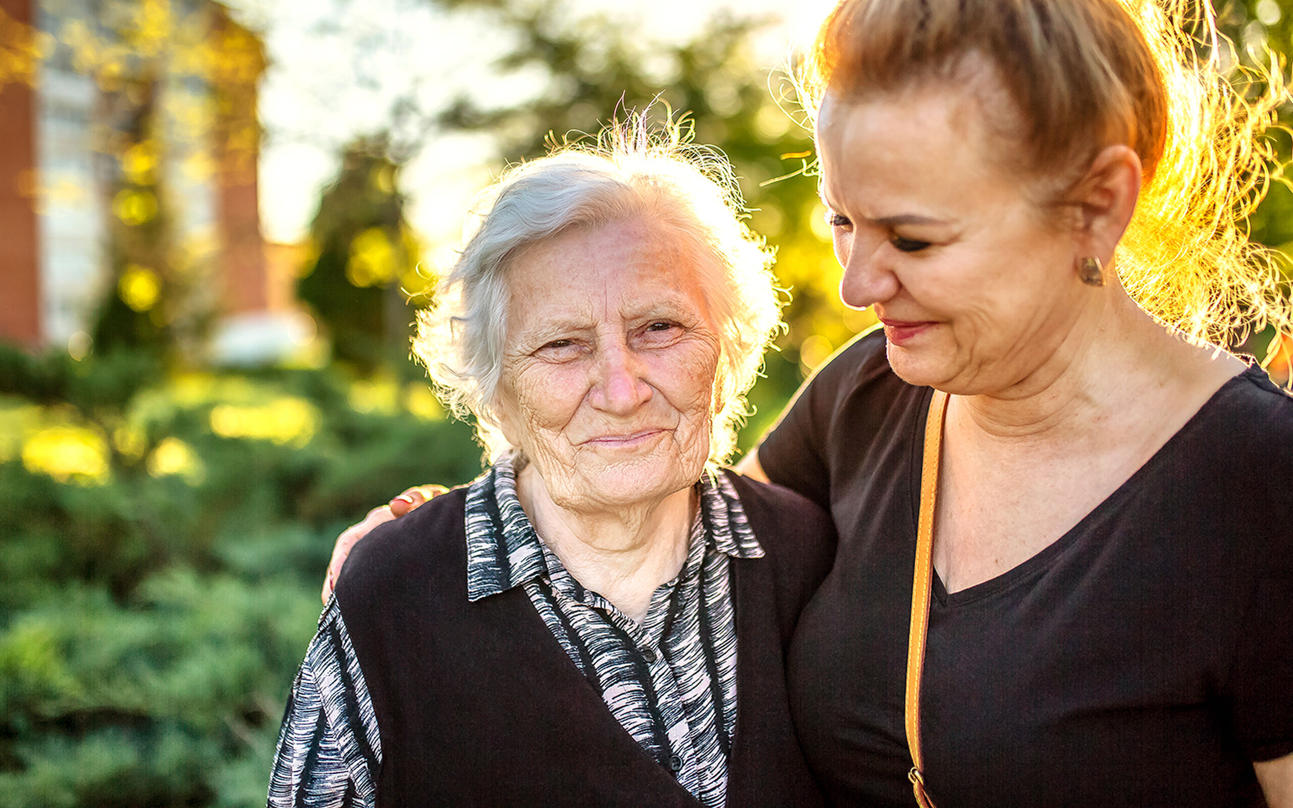 aged care resident smiling while being hugged by a baptistcare aged care worker in the nursing home