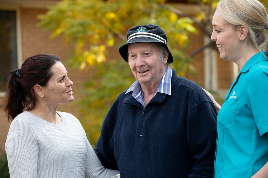 elderly resident smiling outside the nursing home with two aged care home employees