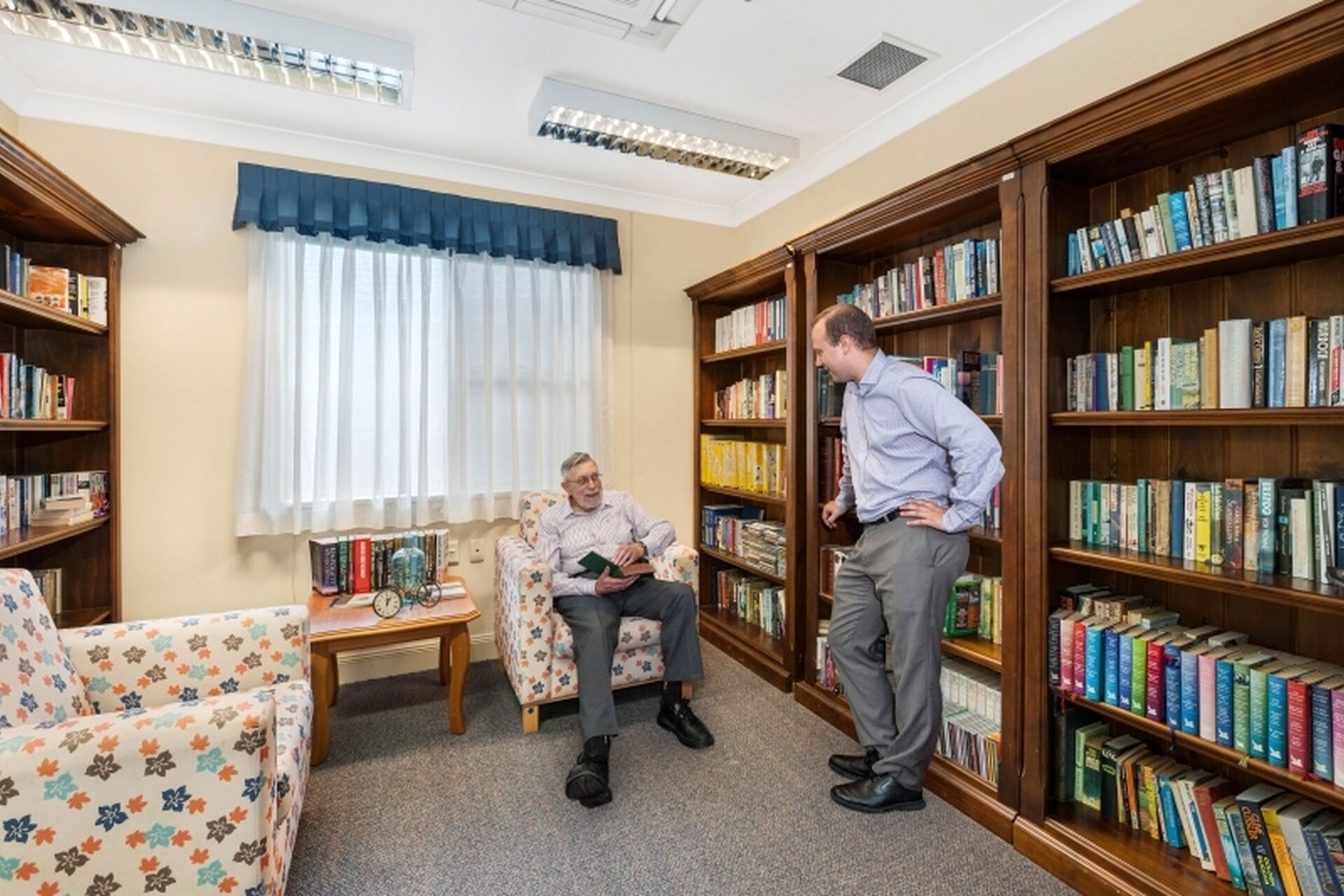 well stocked library with an aged care resident talking to a baptistcare aged care worker at baptistcare warabrook centre aged care home in warabrook newcastle nsw
